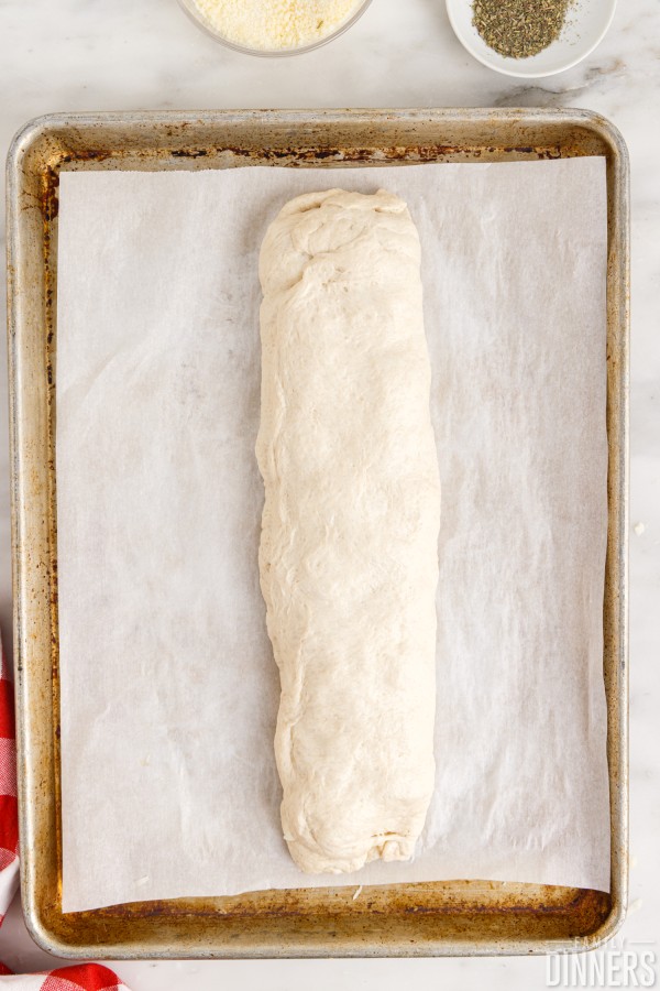 raw dough sub sandwich on baking sheet