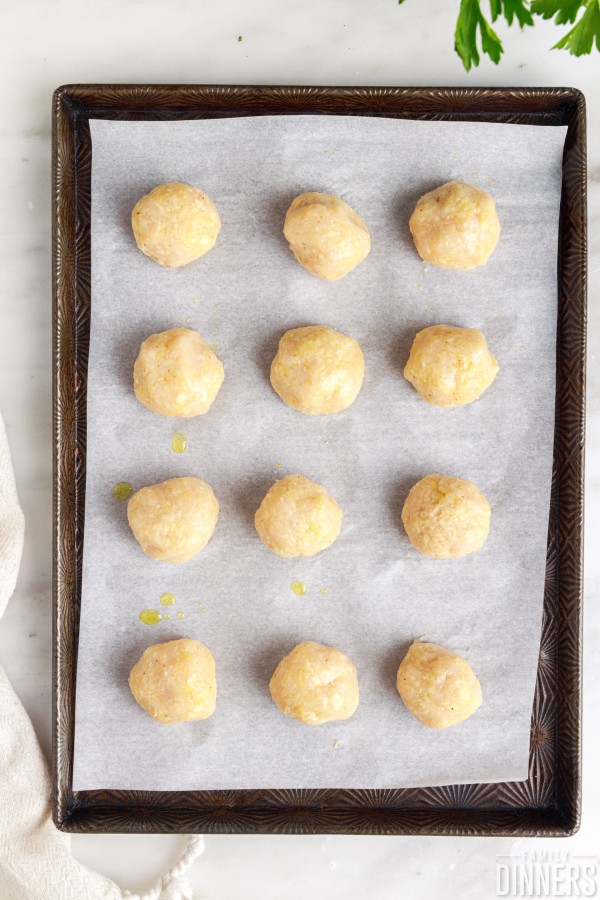 3 rows of 4 uncooked chicken meatballs on a baking sheet
