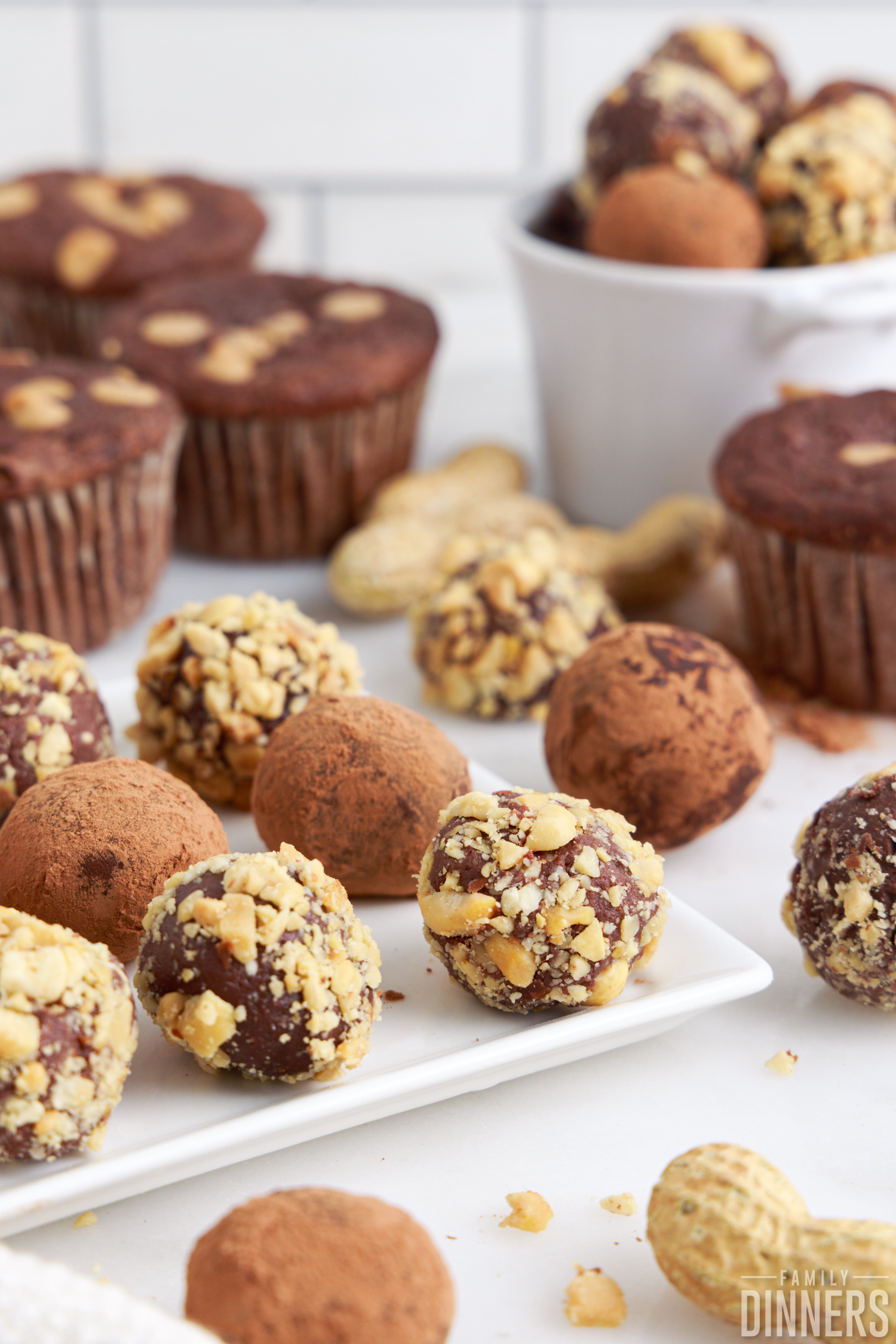 a batch of peanut butter truffles on a tray next to chocolate muffins