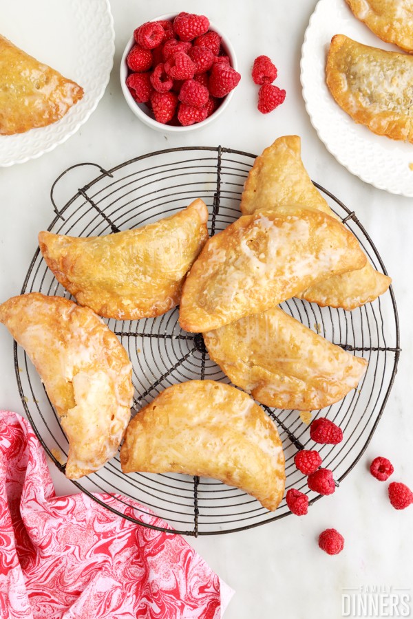 pile of deep fried raspberry hand pies on a round cooling rack