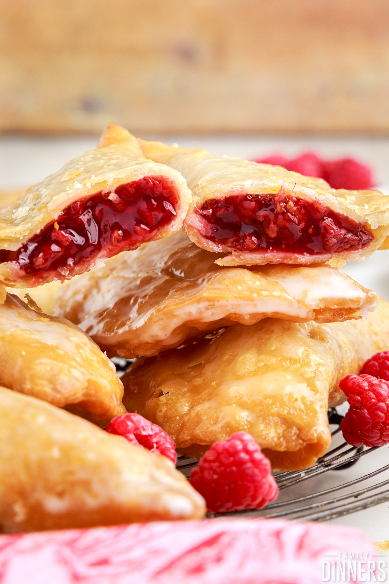 pile of raspberry hand pies, one cut in half showing the filling with some fresh raspberries