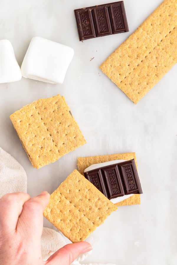 graham cracker being placed on top of s'more