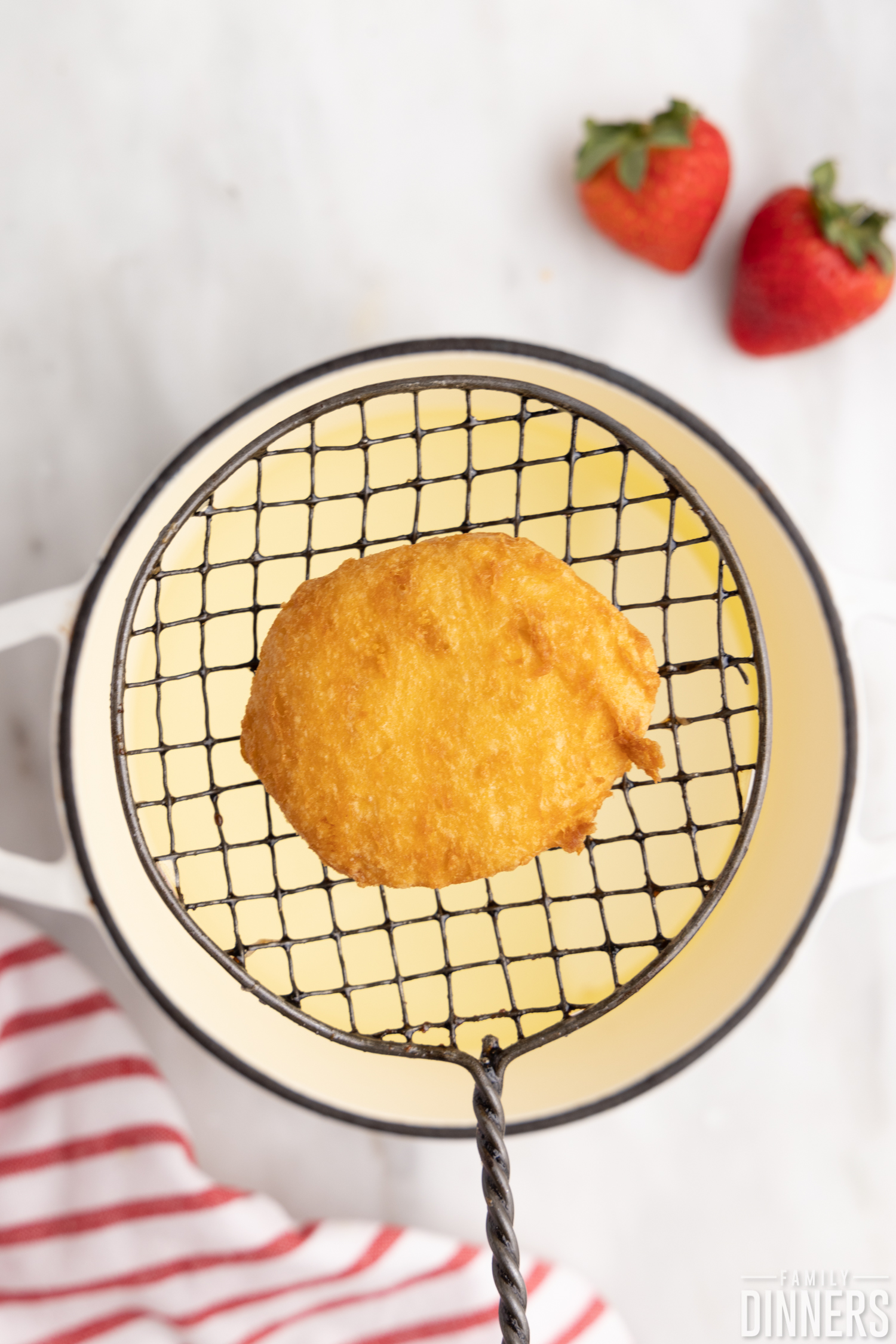 deep fried biscuit on slotted spoon over hot oil pot