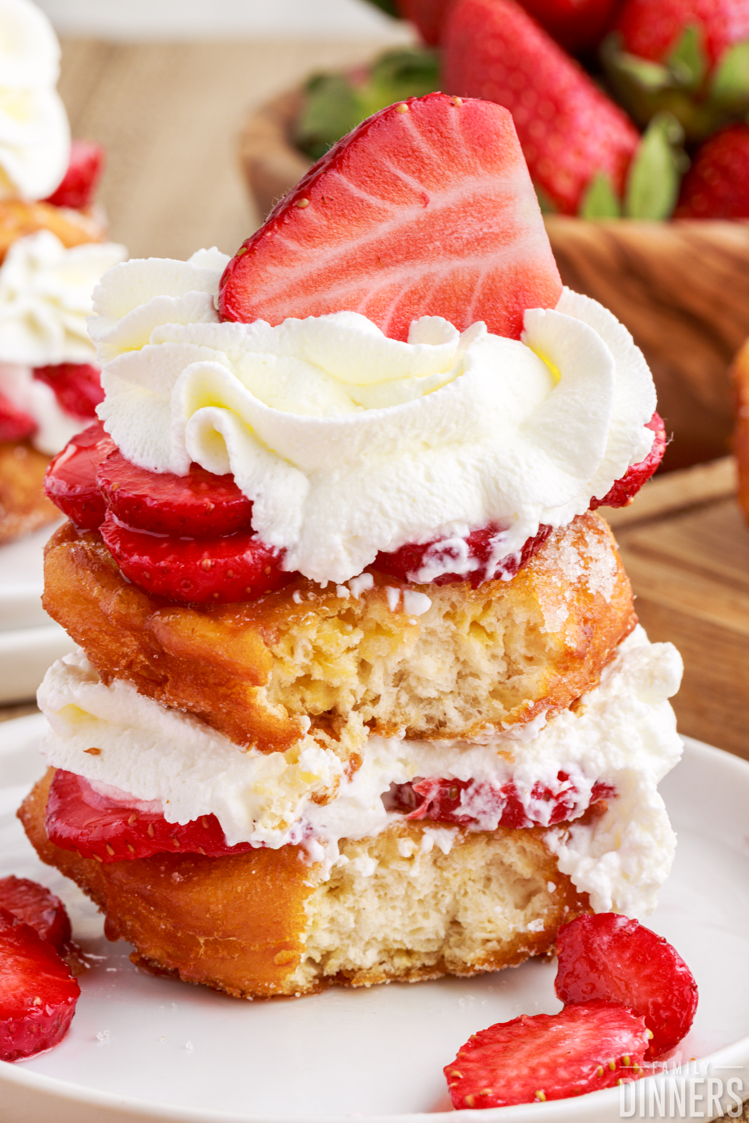 stack of deep fried strawberry shortcake, layered with fresh strawberries and whipped cream on a white plate