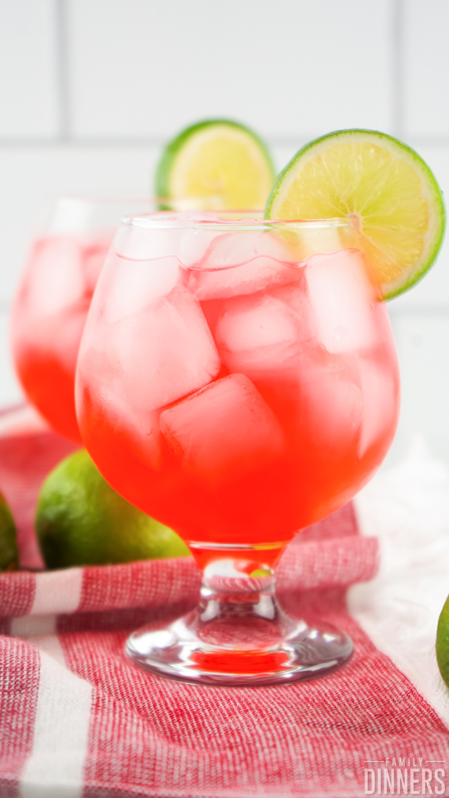 two Dirty Shirley drinks on a table runner with whole limes