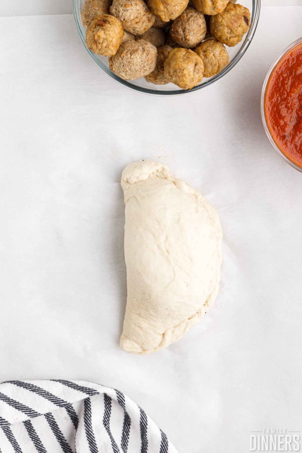 raw calzone on parchment paper