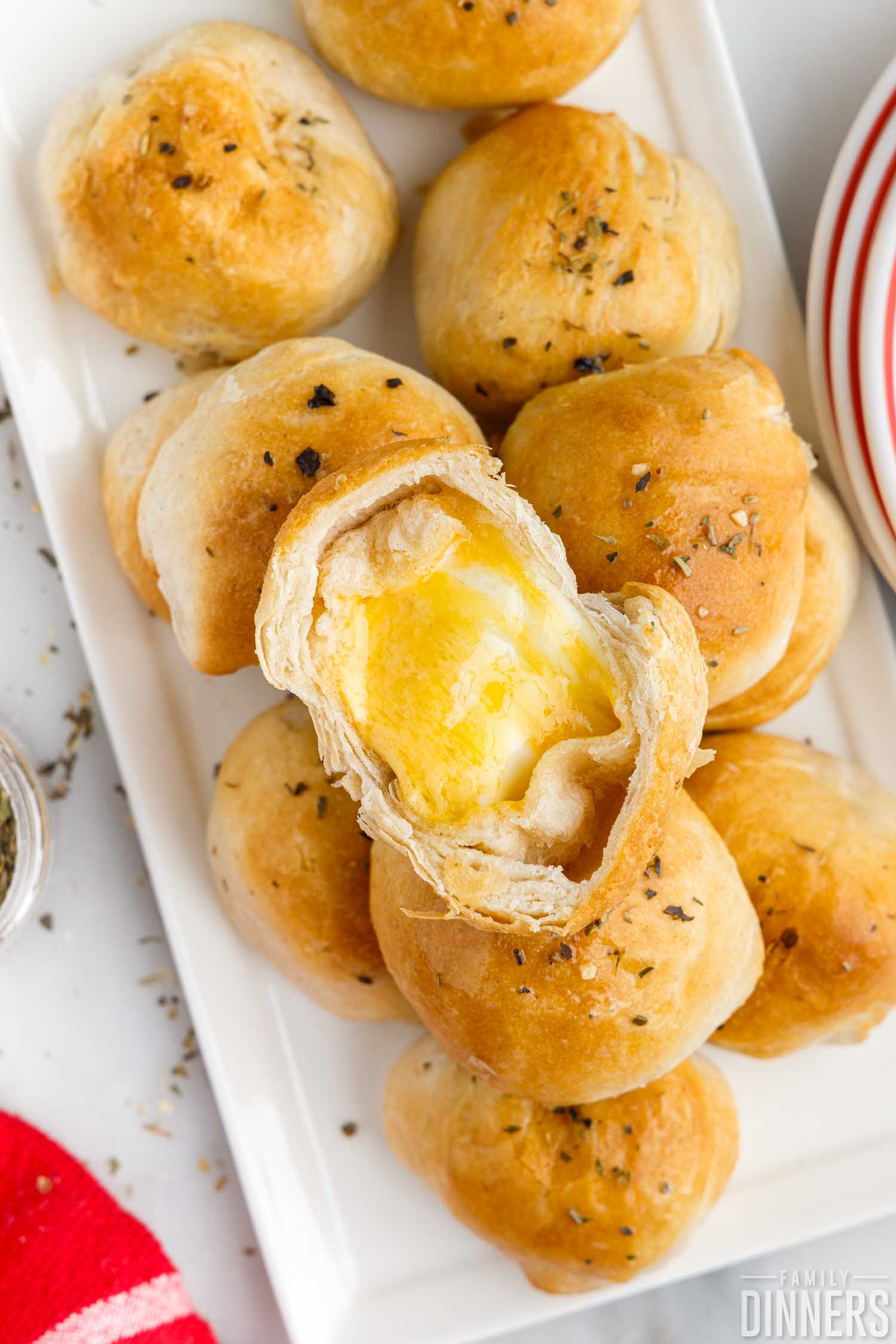 pile of three cheese bombs on a white, rectangular plate, the top one is showing the cheese filling