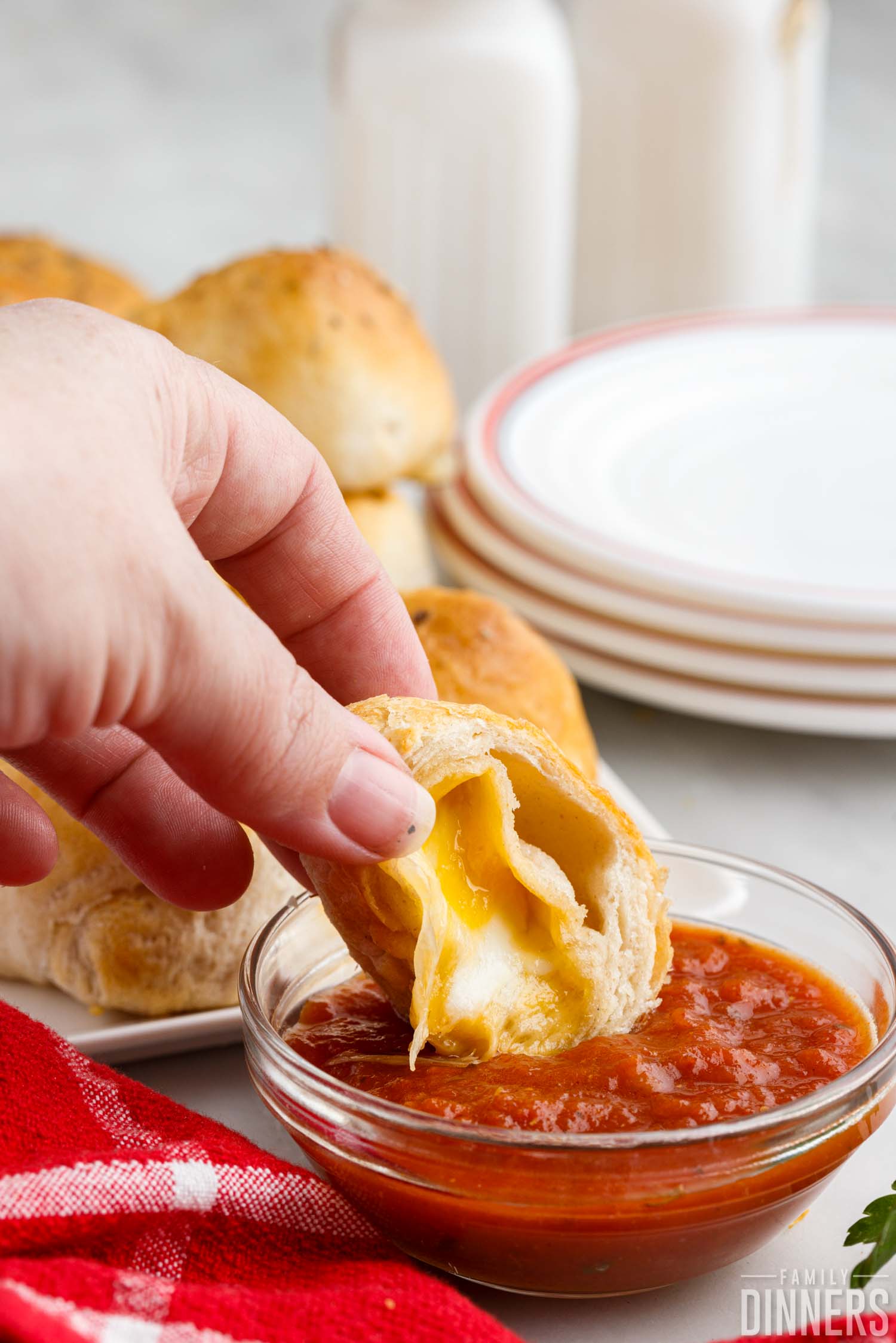 an open cheese bomb being dipped in marinara sauce