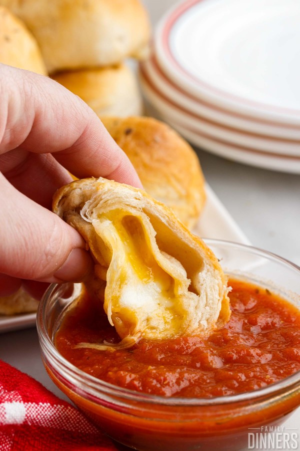 open three cheese bomb being dipped into marinara sauce