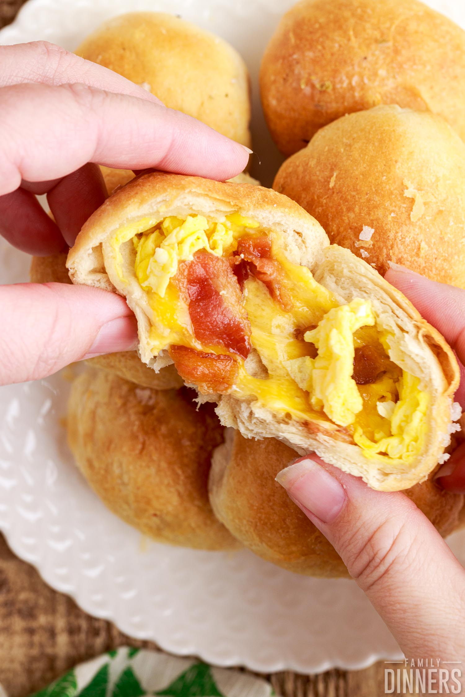 pile of breakfast biscuit bits on a plate, hands holding half a biscuit bite exposing the filling