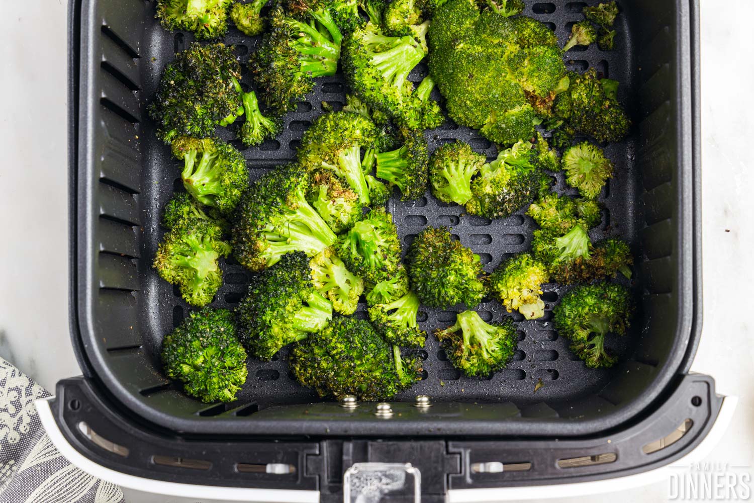 pile of cooked broccoli in the air fryer basket.