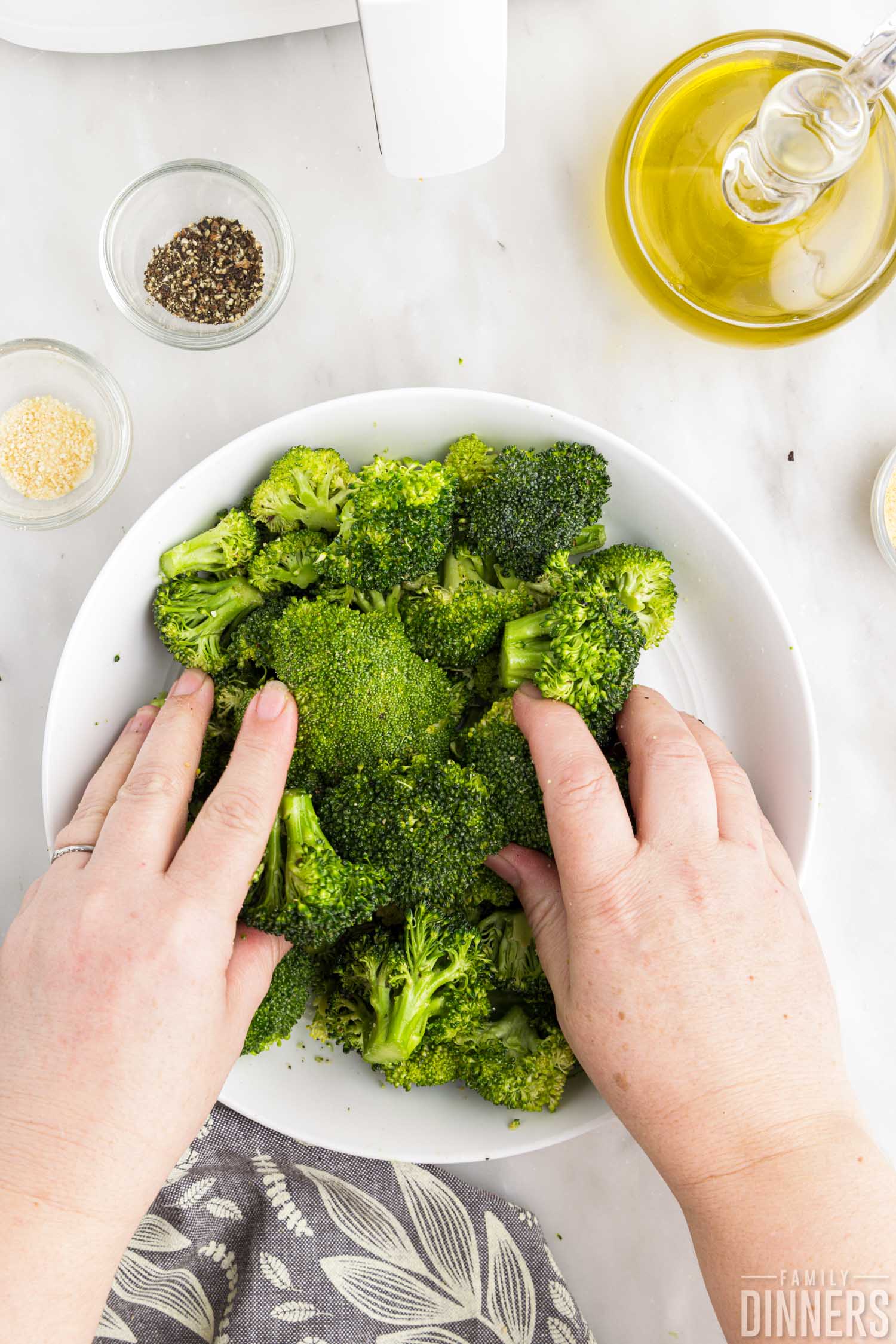 hands tossing broccoli.