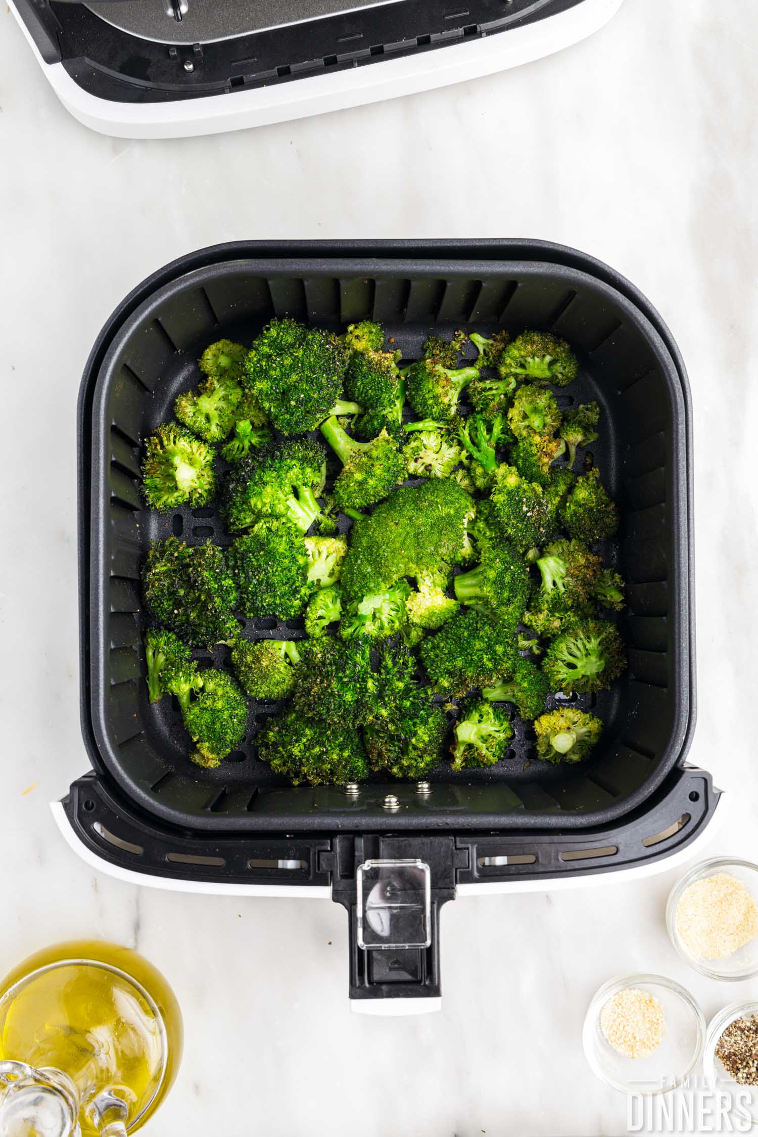 cooked broccoli in air fryer basket.