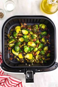 cooked brussels sprouts with bacon in air fryer basket.