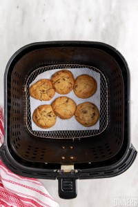cooked chocolate chip cookies in air fryer basket.