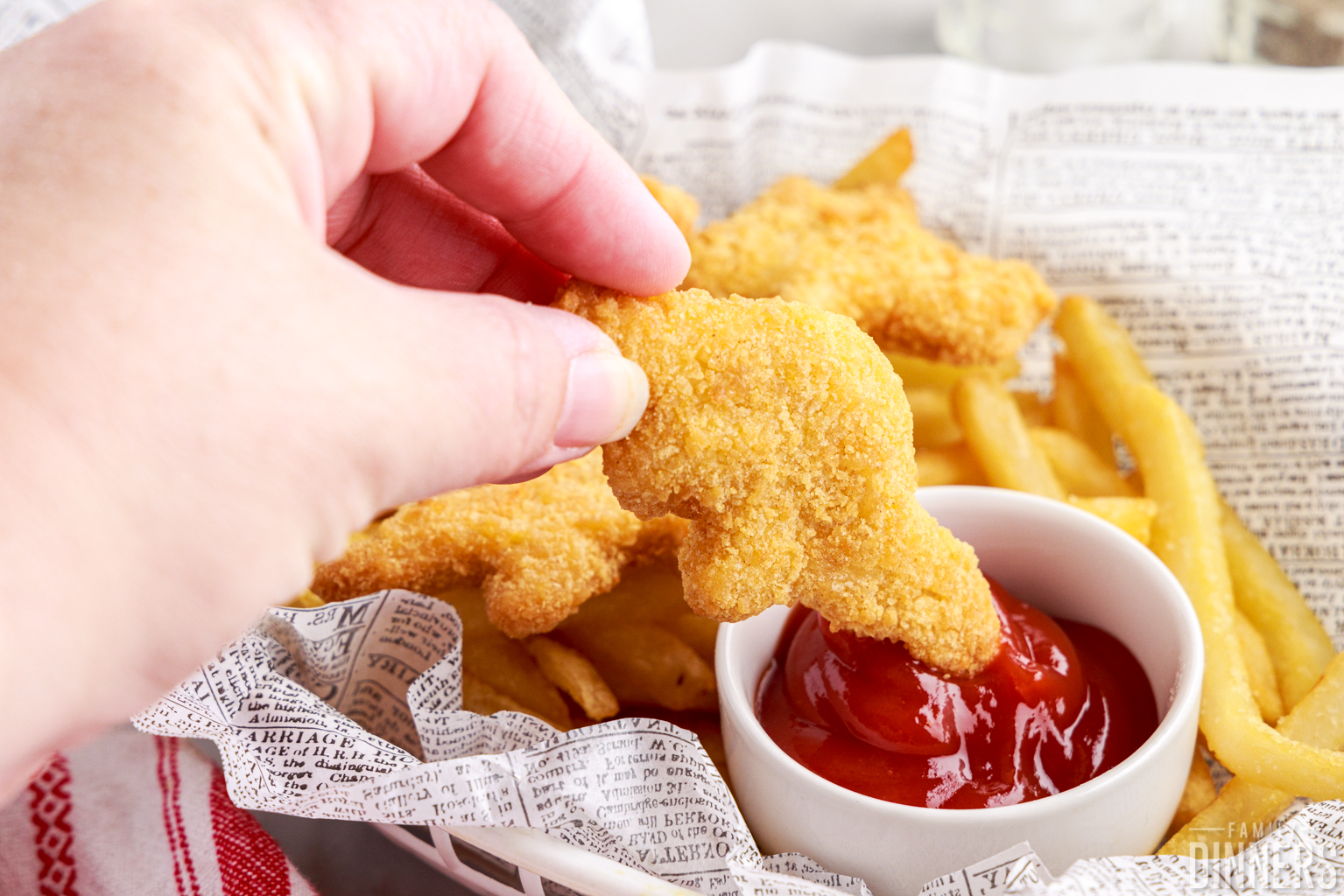 hand holding chicken nugget dipped into ketchup