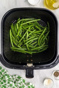 Uncooked green in air fryer basket.