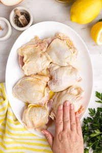 hand patting oil on chicken.