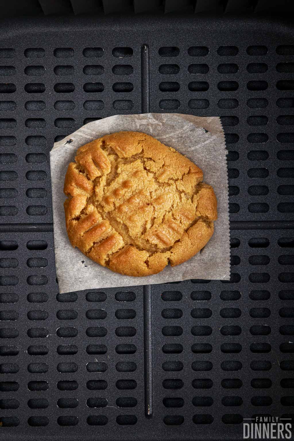 Cooked cookie in air fryer basket.