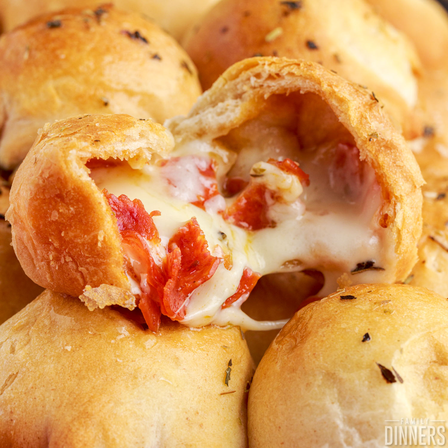 pile of game day appetizer pizza bites, one open with filling oozing out