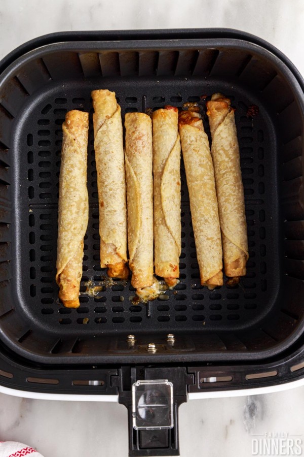 cooked frozen taquitos in air fryer basket.