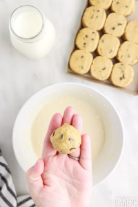 cookie dough ball in a hand over batter.