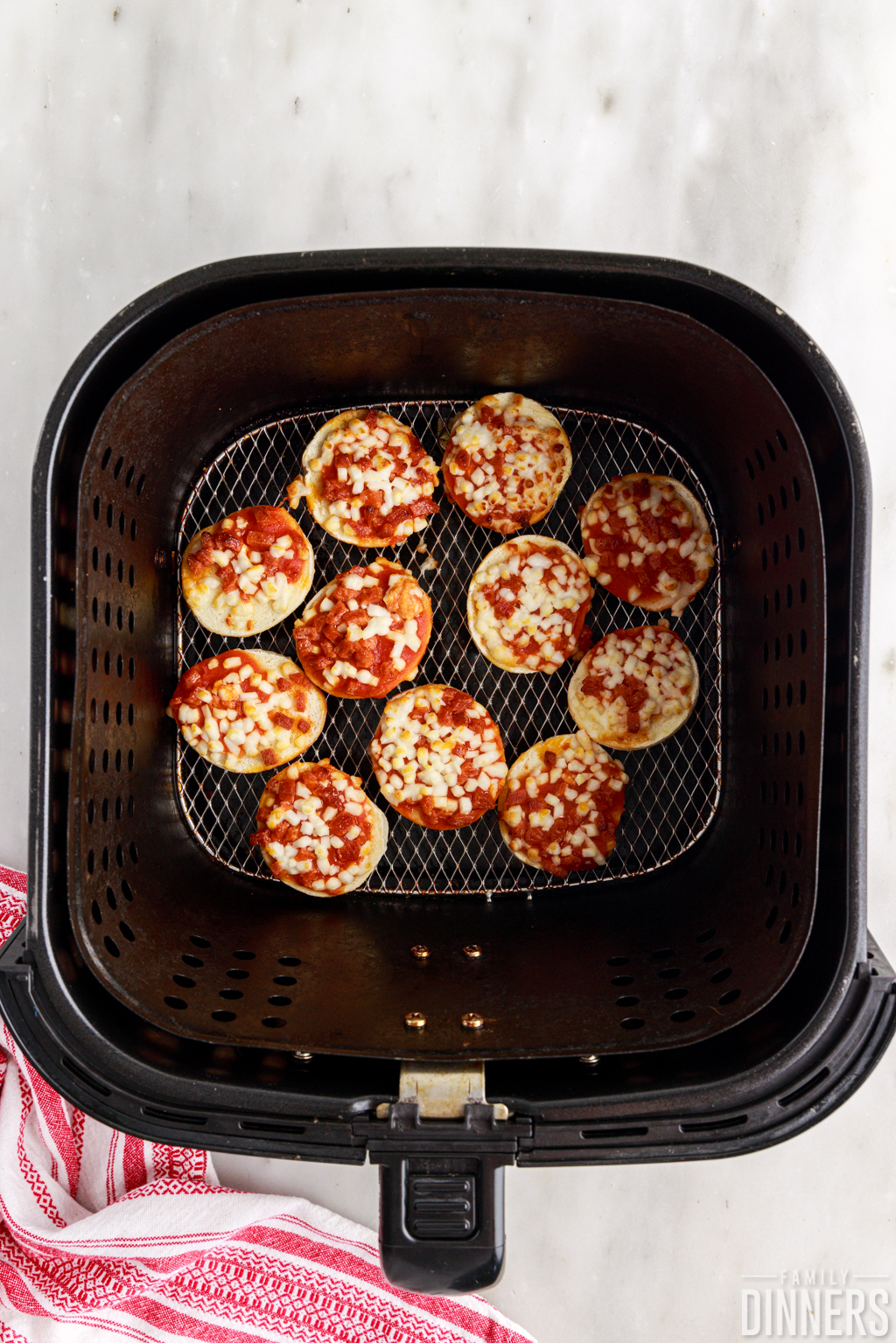 Cooked bagel bites in the air fryer basket.