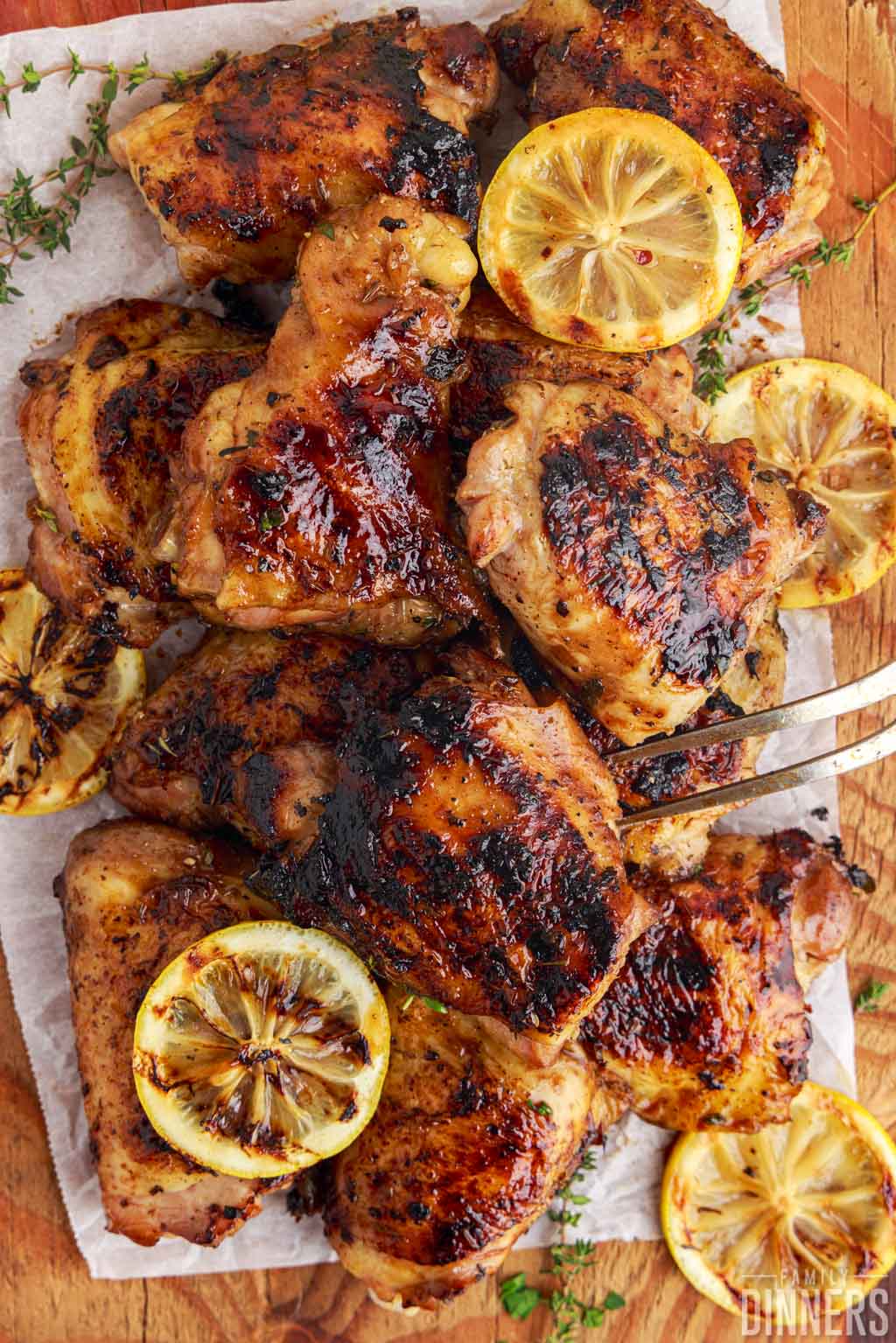 pile of grilled chicken on a wooden board with lemons