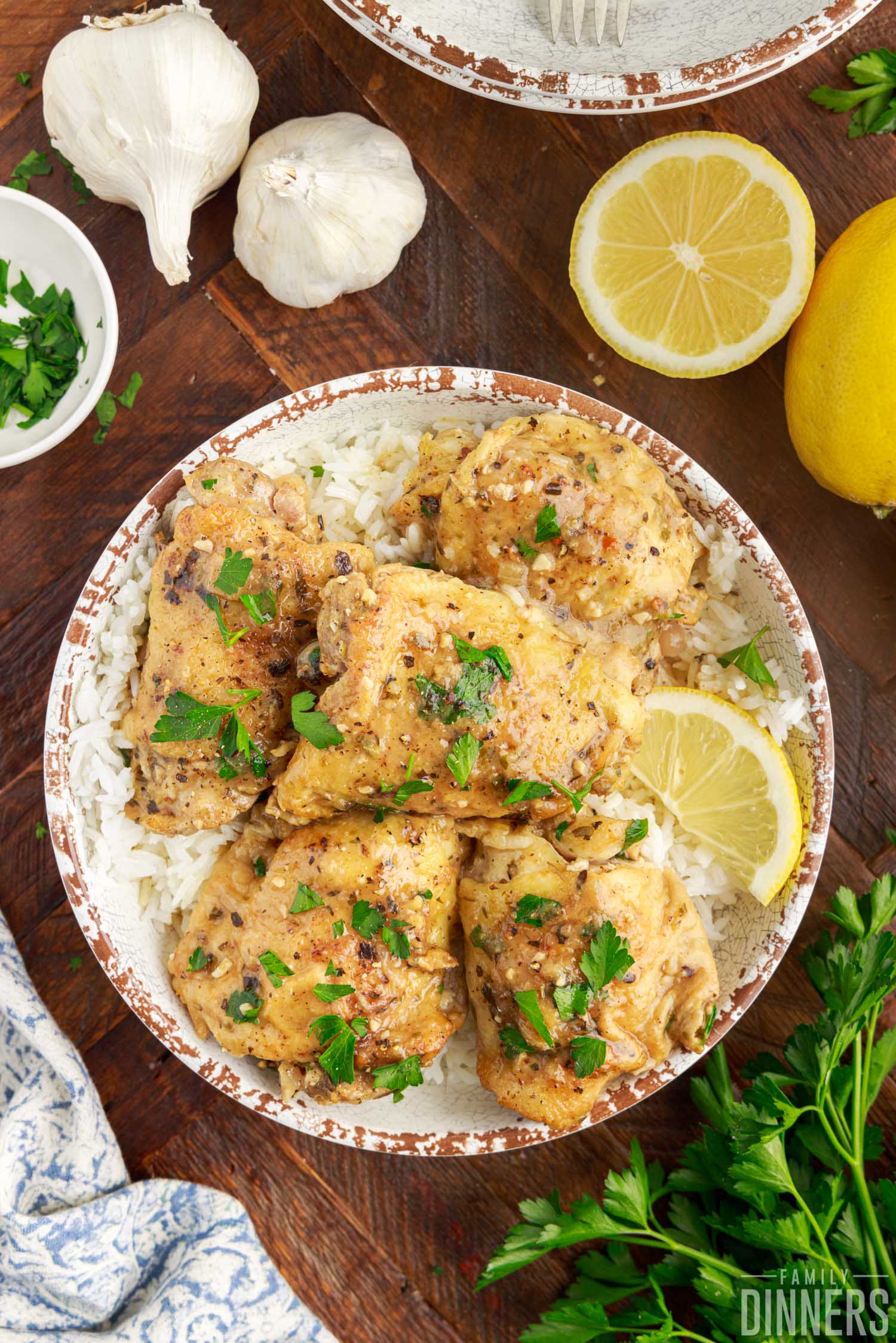 Lemon butter chicken thighs on a plate with rice and fresh lemons