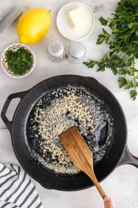 Stirring butter and garlic in a pan.