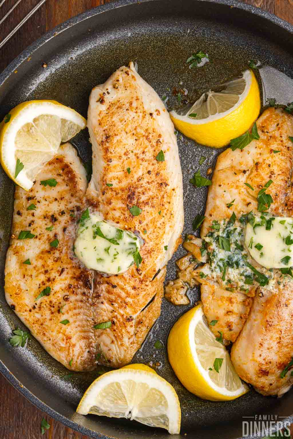 pan seared tilapia with lemon butter in a pan.