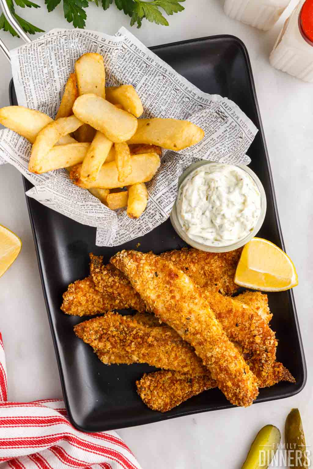 fried fish with fries, tartar sauce and a lemon wedge