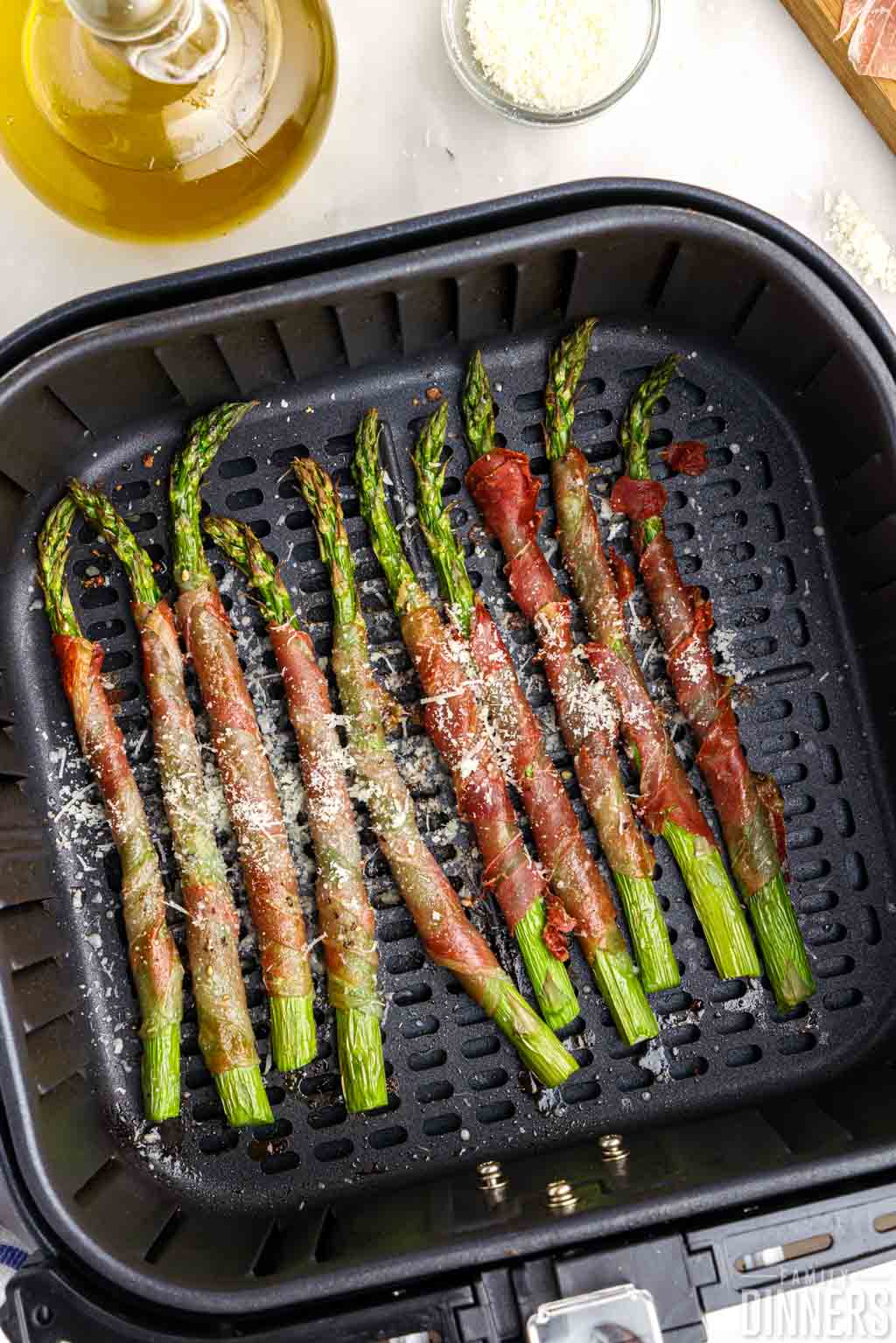 Cheese sprinkled over cooked prosciutto wrapped asparagus.