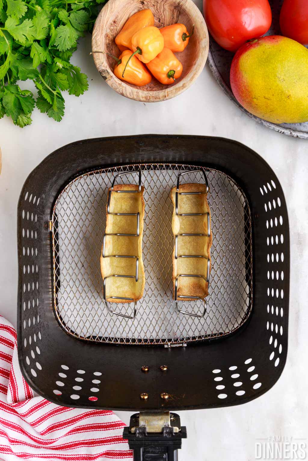 Cooked taco shells in an air fryer basket.