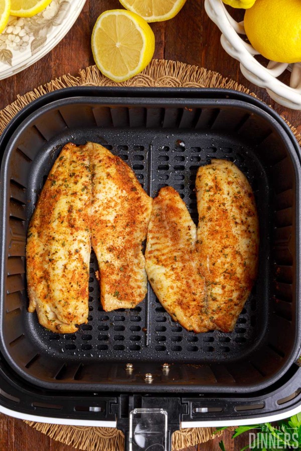 Cooked air fryer tilapia in the air fryer basket.