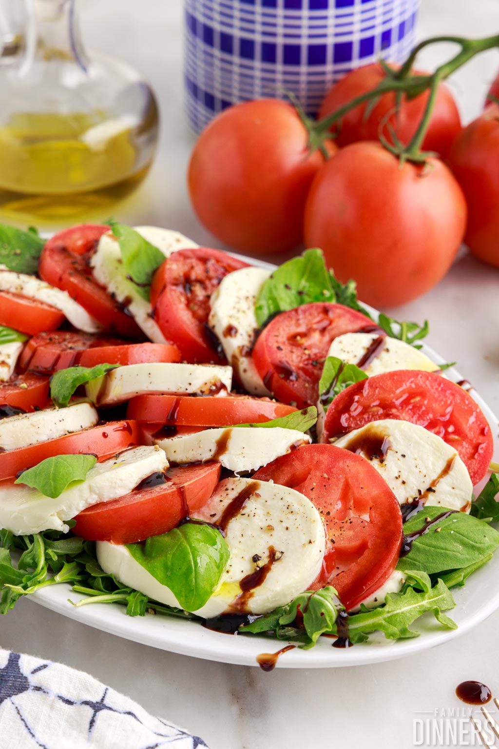 close up of tomatoes, mozzarella and basil on a plate, drizzled with balsamic glaze