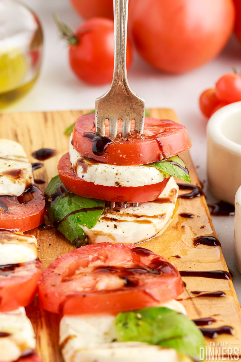 Caprese salad (tomato and mozzarella nd basil with oil and vinegar) stacked on a fork.