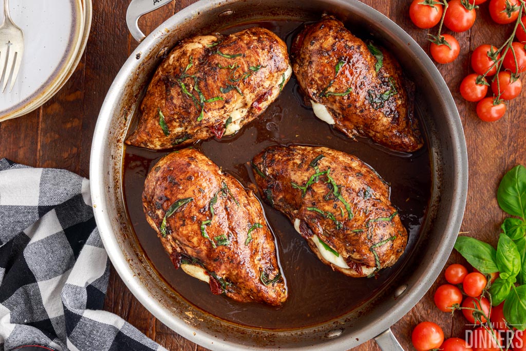 Chicken stuffed with cheese, tomatoes and sun dried tomatoes in a skillet.