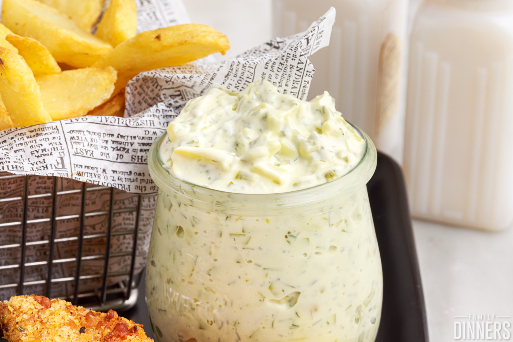 tartar sauce in a glass jar next to a basket of fries