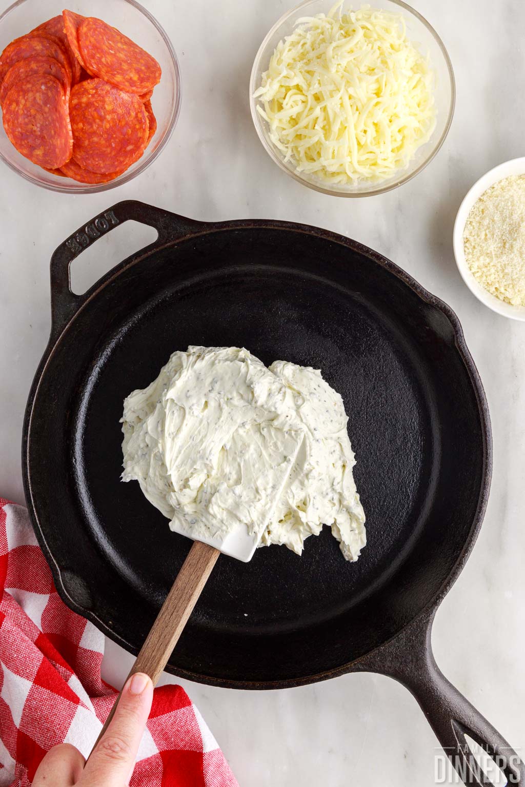 spatula spreading cream cheese mixture into cast iron pan