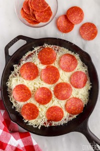 Cheese and pepperoni topped dip in cast iron pan.