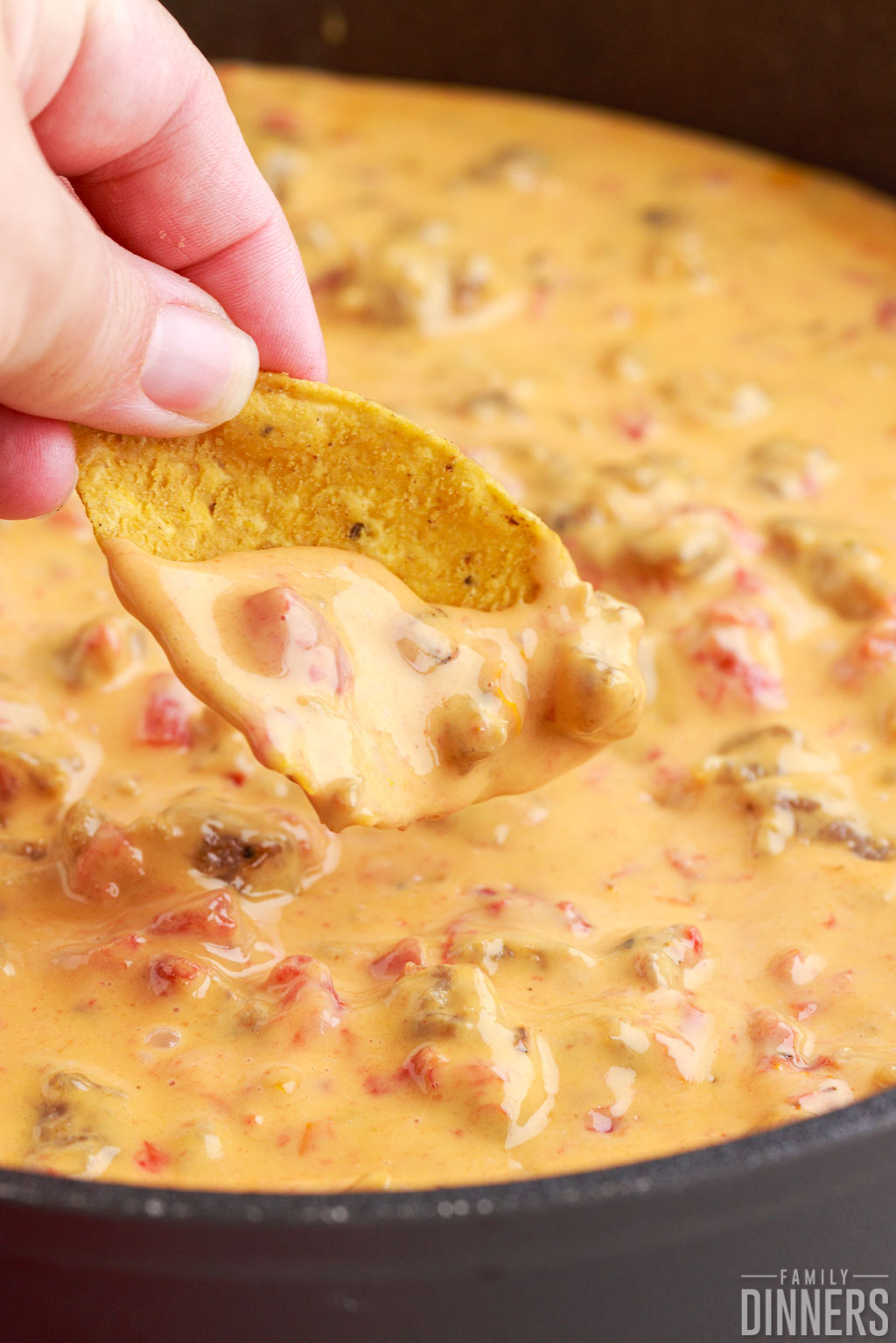 hand dipping a chip in warm rotel dip