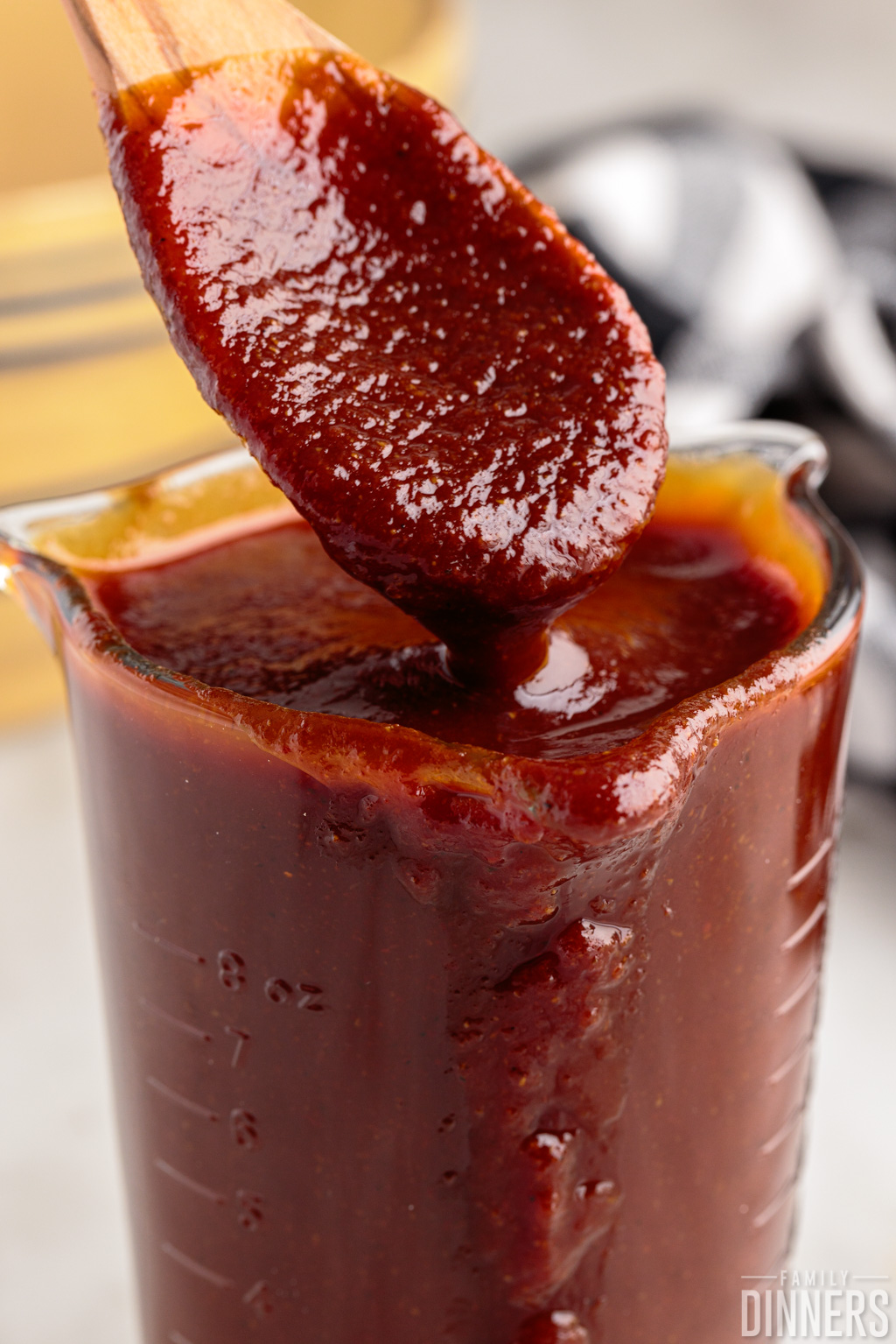 BBQ sauce in a jar with a spoon scooping some out.