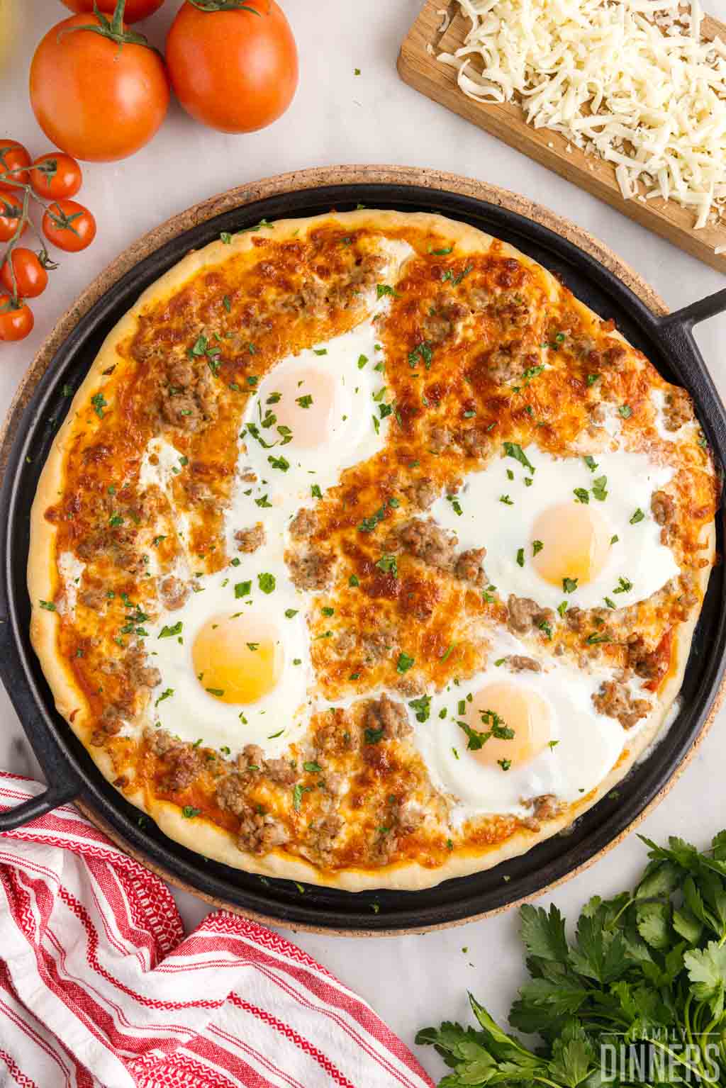Large sausage breakfast pizza with eggs on top on a cast iron pizza pan.