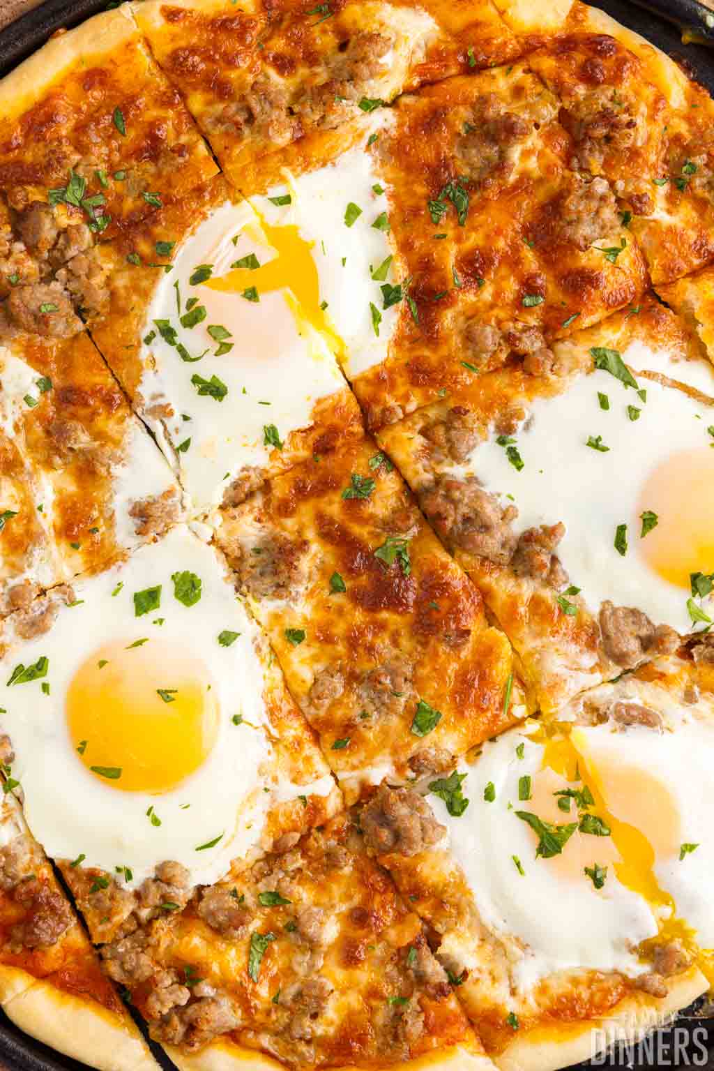 Sliced sausage breakfast pizza with sunny side up egg on top.