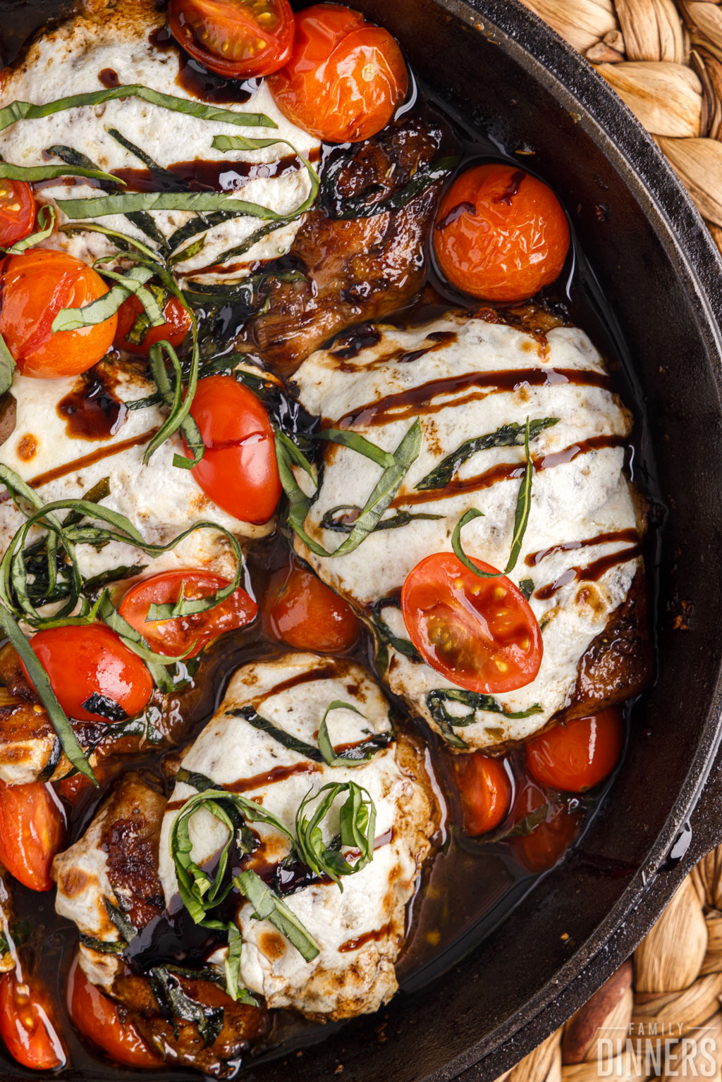 caprese chicken thighs in a pan sprinkled with basil