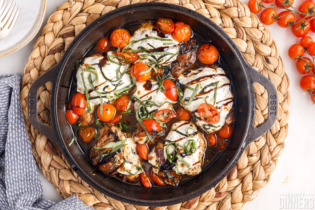 Caprese chicken with mozzarella and tomatoes in a skillet.
