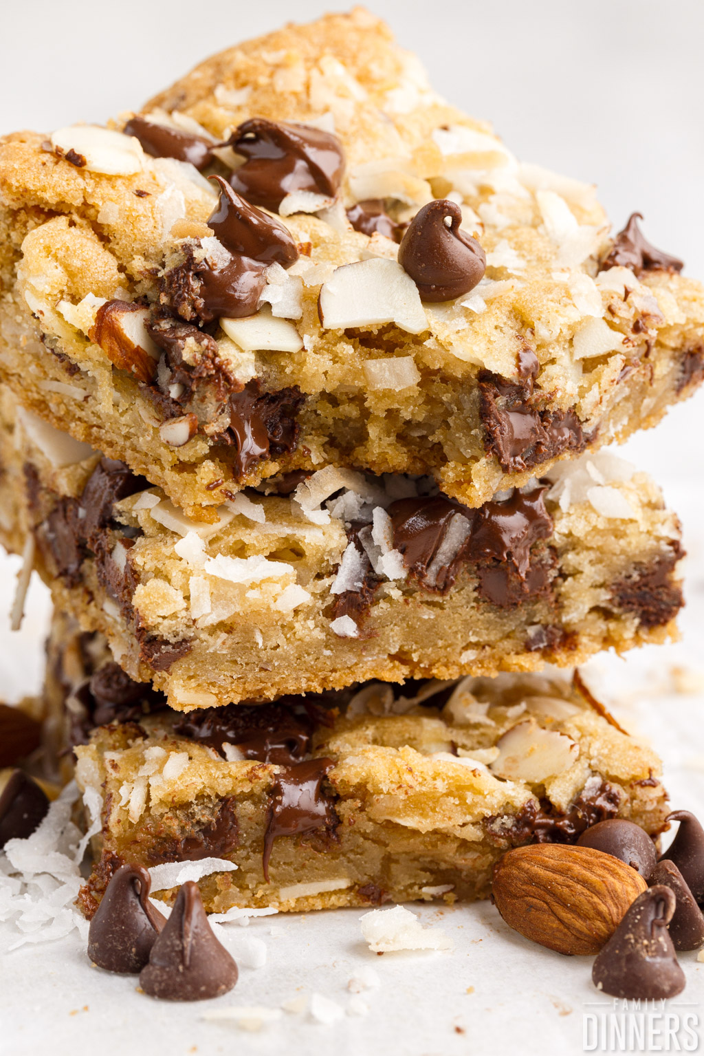 Stack of chocolate coconut bars, one with a bite taken out.