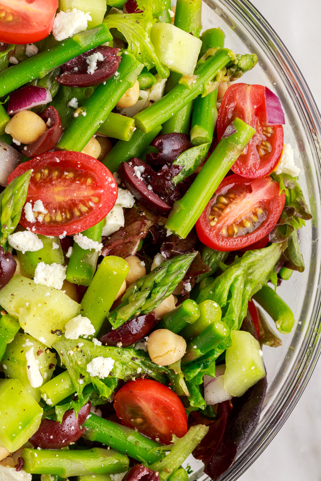 close up of chopped asparagus salad with tomatoes, olives and chickpeas