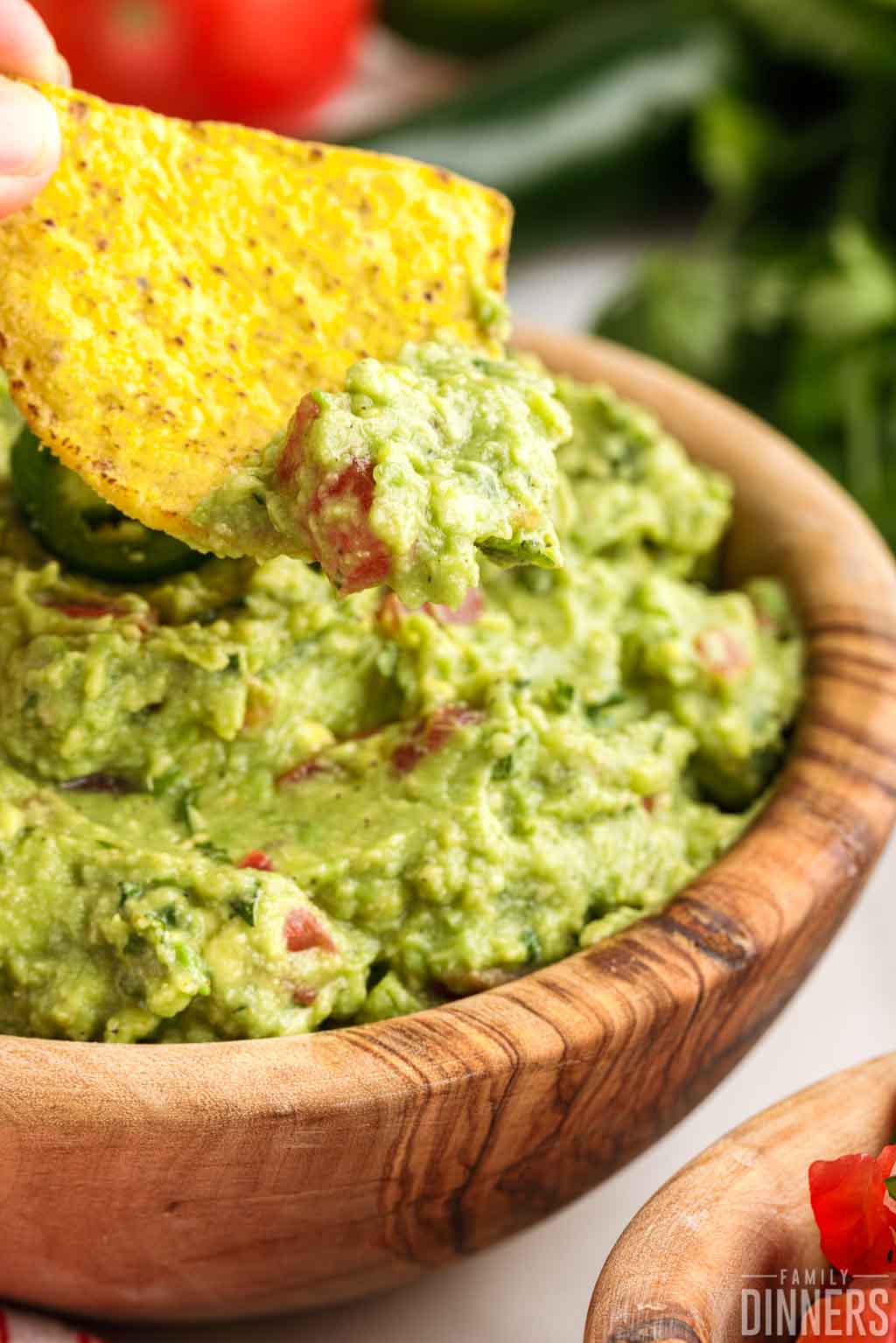 close up of a chip dipped in guacamole over a bowl of guacamole